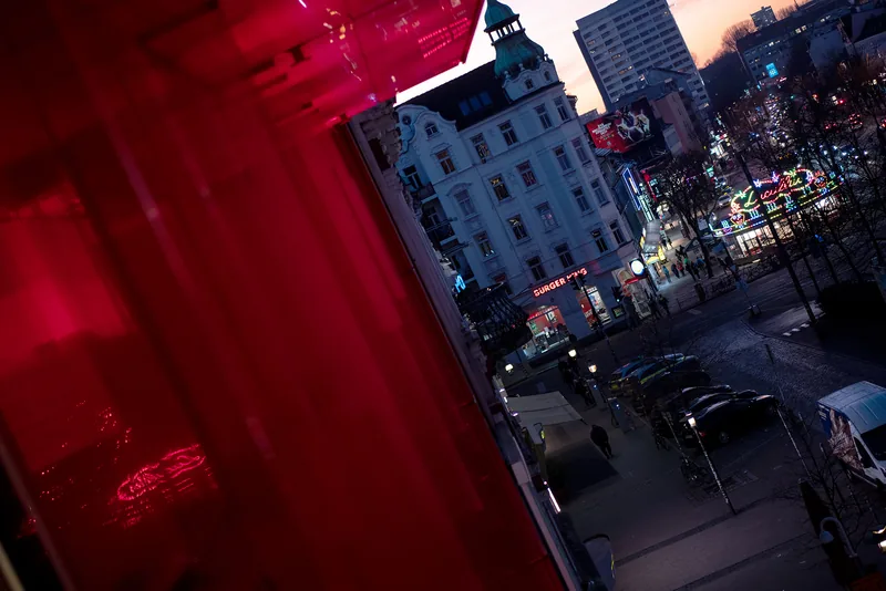 View through red glass onto the street at dusk.