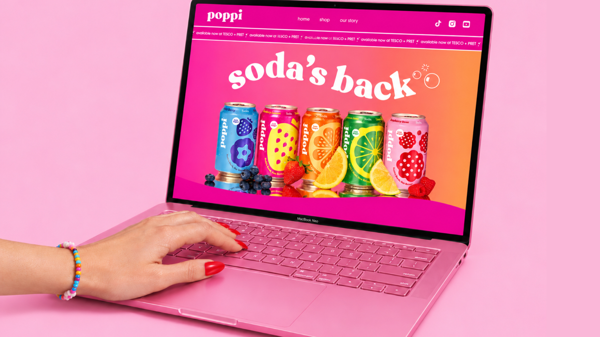 Laptop mit poppi Website auf einem pinkfarbenen Tisch