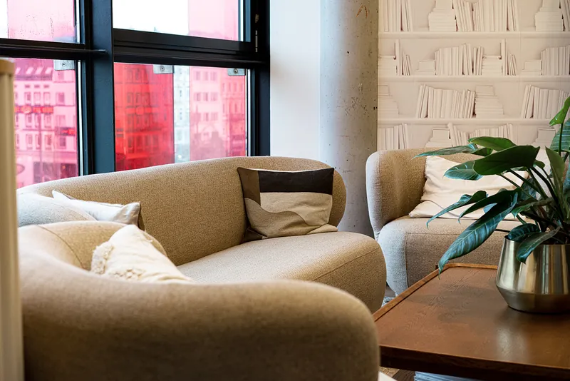 Bright lounge with a sofa and plants at the Hamburg office